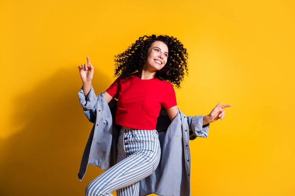 Photo of lovely girl fingers look empty space dance wear striped jeans cropped red t-shirt jacket isolated yellow color background - Fotoğraf, Görsel
