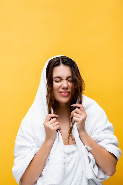 όμορφη γυναίκα με κλειστά μάτια, βρεγμένα μαλλιά και πετσέτα απομονωμένη στο κίτρινο - Φωτογραφία, εικόνα