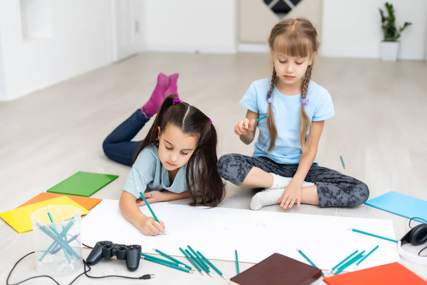 Słodkie dzieci malują i uśmiechają się leżąc na podłodze w domu - Zdjęcie, obraz