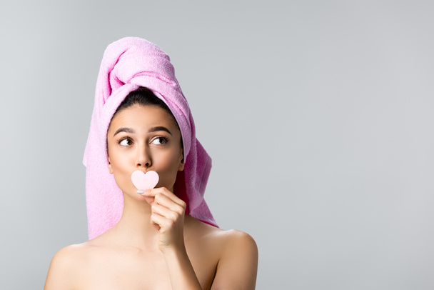 beautiful woman with towel on hair holding heart shaped sponge isolated on grey - Photo, Image