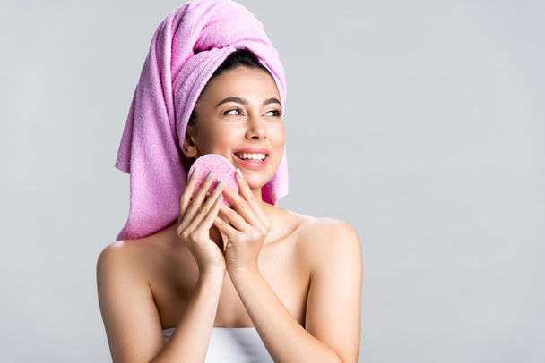 sourire belle femme avec serviette sur le visage de nettoyage des cheveux avec éponge isolé sur gris - Photo, image