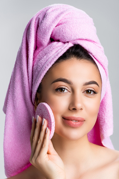 beautiful woman with towel on hair using sponge on face isolated on grey - Foto, Imagen