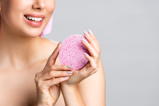 cropped view of smiling beautiful woman with towel on hair and sponge isolated on grey - Foto, afbeelding