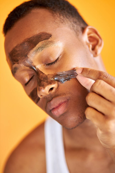 good-looking african american male is taking off black facial mask - Fotó, kép