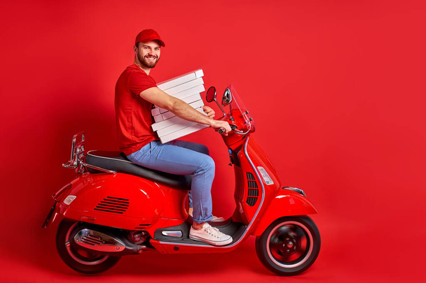 nice caucasian male guy driving moped motorcycle bringing pile stack pizza order - Фото, зображення