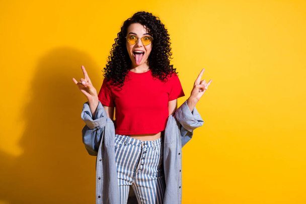 Photo of lovely lady tongue-out show horns wear red t-shirt striped jeans jacket isolated yellow color background - Foto, Bild