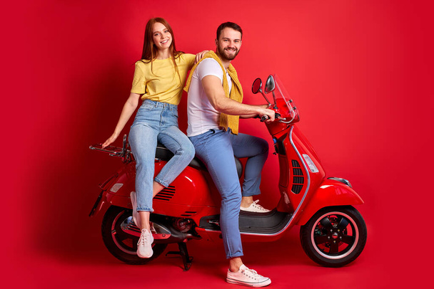 beautiful caucasian couple on motorcycle isolated on red background - Zdjęcie, obraz