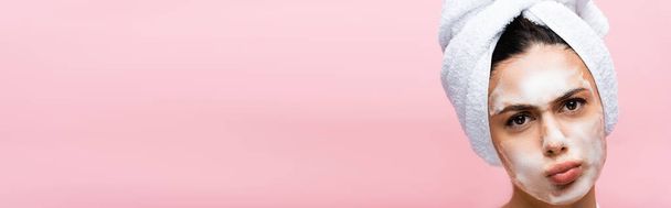 hermosa mujer con toalla en el cabello y espuma en la cara mueca aislado en rosa, pancarta - Foto, imagen