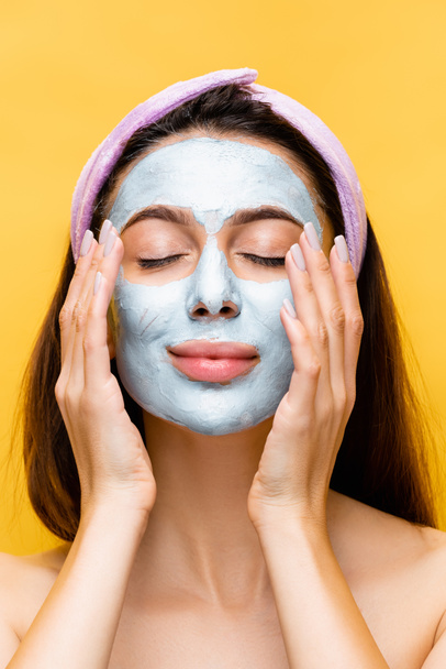 beautiful woman with clay mask on face and closed eyes isolated on yellow - Photo, image