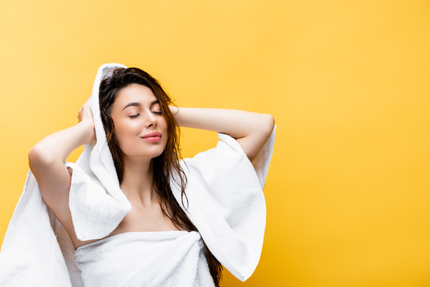 sourire belle femme aux cheveux mouillés et serviette isolée sur jaune - Photo, image