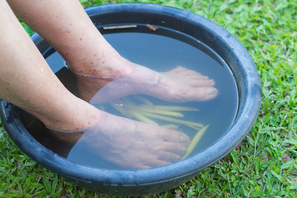 Close-up of spa foot with herbs water for relaxation treatment. A senior woman has ankle pain use herbal treatment to relax the muscles by soaking warm water that is boiled from herbs. - Photo, Image