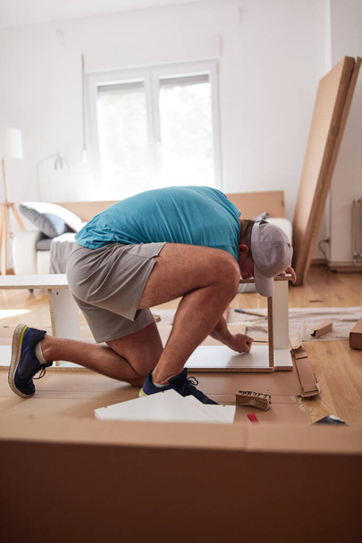 Handyman werknemer monteren meubels in een nieuw appartement, verhuizen en hardwerkende. - Foto, afbeelding