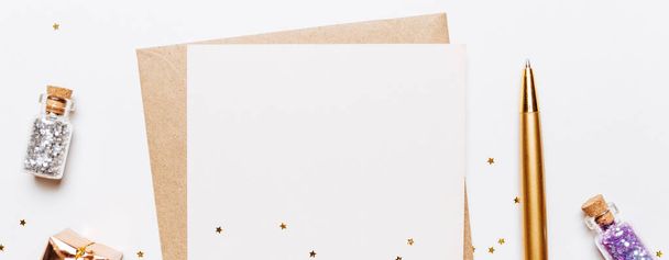 Blank note with envelope, gifts, pen and gold glitter stars on white background - Fotó, kép