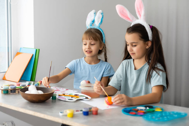 Two little cute girls painting on Easter eggs - Photo, Image