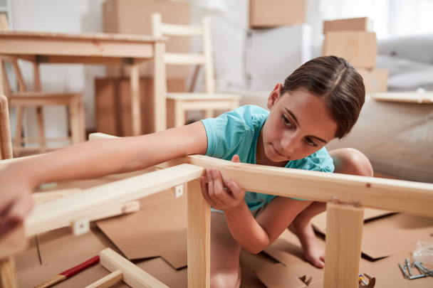 Small girl assembling furniture in new apartment, moving in and being hardworking. - Foto, imagen