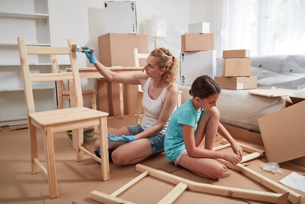 Mãe e filha pintura e montagem de móveis em novo apartamento, movendo-se e sendo trabalhador. - Foto, Imagem