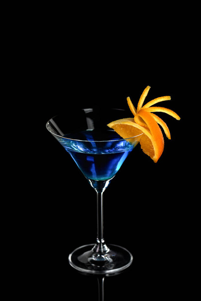 Decorazione per un cocktail di arancia. Presentazione elegante e originale. Martini Blue Curacao su sfondo nero - Foto, immagini