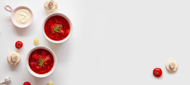 Traditional home Ukrainian beet soup with fresh green dill. Russian borscht in bowl of tomatoes, sour cream, and mushrooms on a white background with copy space - Foto, Imagem