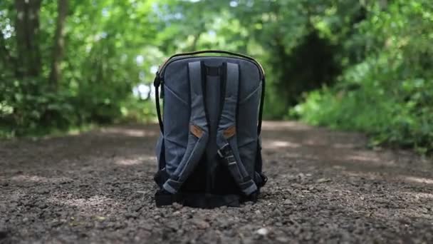 Fotoğrafçılık ekipmanları için gri bir sırt çantası bir parkta kirli bir yolda - Video, Çekim