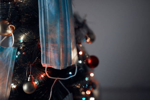 外科用マスクで飾られたクリスマスツリー-ウイルスパンデミック2020/2021社会的距離、ロックダウンと隔離隔離へのイラスト. - 写真・画像