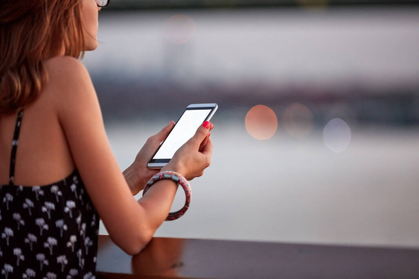 Giovane donna in possesso di cellulare con schermo bianco in bianco nei dintorni della città urbana. - Foto, immagini