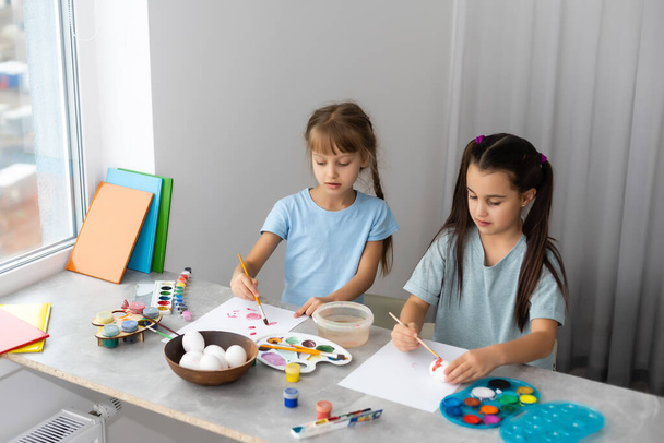 δύο μικρά κορίτσια με πινέλο ζωγραφική στο τραπέζι, εκπαίδευση, ακουαρέλα, σχέδιο, Δημιουργικότητα έννοια. - Φωτογραφία, εικόνα
