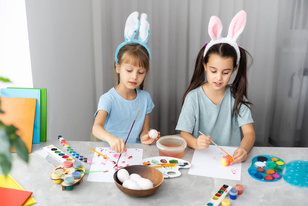 dos hermanas lindas niñas felices pintar huevos de Pascua, oh risa, mostrar huevos y manos pintadas - Foto, imagen