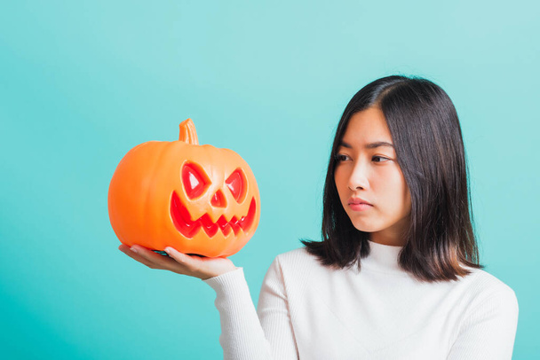 Portrait of Asian beautiful young woman holding orange model pumpkins, funny happy female with ghost pumpkins, studio shot isolated on blue background - Photo, Image