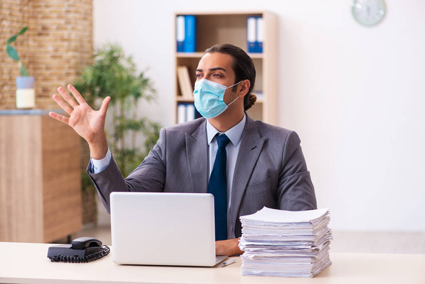 Mladý muž zaměstnanec nosí masku během pandemie - Fotografie, Obrázek