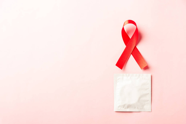 Red bow ribbon symbol HIV, AIDS cancer awareness and condom with shadows, studio shot isolated on pink background, Healthcare medicine sexually concept, World AIDS Day - Fotoğraf, Görsel