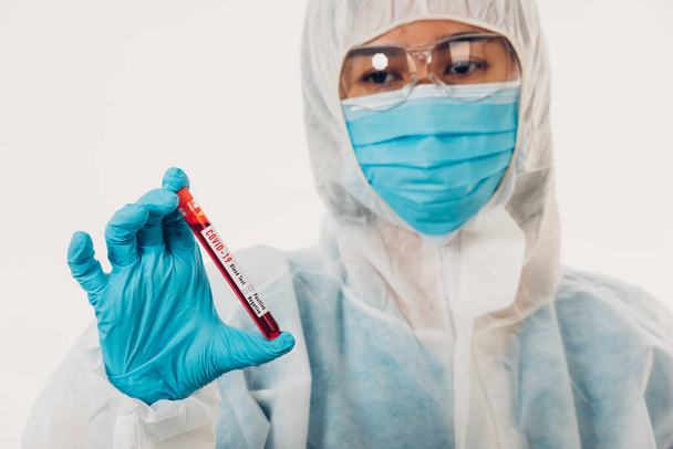 Medical scientist in PPE uniform wear a mask holding test tube Coronavirus test blood sample in a hospital laboratory for analyzing isolated on white, medicine COVID-19 pandemic outbreak concept - Photo, image