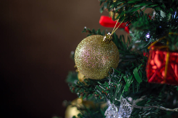 Διακοσμημένο χριστουγεννιάτικο δέντρο. Τα Χριστουγεννιάτικα παιχνίδια κλείνουν. Διακόσμηση διακοπών. Χρυσή χριστουγεννιάτικη μπάλα - Φωτογραφία, εικόνα