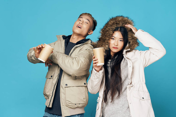 Homme et femme tenant des tasses à café dans les mains vêtements d'hiver réchauffement boisson communication studio de mode  - Photo, image