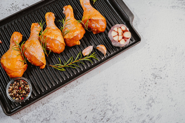 Marinated chicken drumstick in a grill pan with green rosemary. - Photo, Image