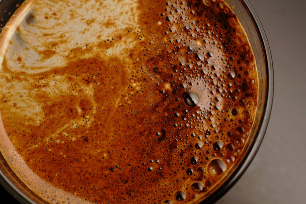 Cup of coffee top view. On a dark background and in semi-darkness. A beautiful drawing of the foam. - Fotó, kép