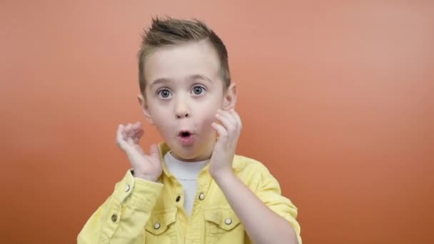 Zabawny chłopiec w żółtej koszuli bardzo zaskoczony, niespodziewane sprzedaży i rabaty - Materiał filmowy, wideo