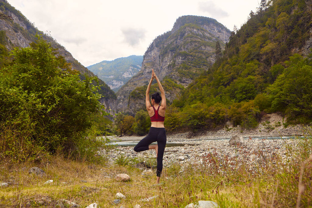 Jógaórák a természetben. Egy nő jógázik a hegyekben, a hegyi folyó közelében. A koncepció a sport egyedül. Szociális kirekesztés - Fotó, kép