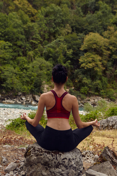 Jógaórák a természetben. A koncepció a sport egyedül. Társadalmi kirekesztés Egy nő jógázik a sziklákon, a hegyi folyó közelében. - Fotó, kép