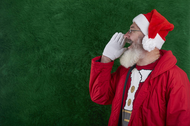 Mature bearded man with eyeglasses on face wearing Santa hat, Santa put hand to face and shouts, copy space - Foto, imagen