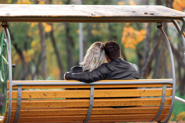 Para zakochanych w parku przytula się jesienią. Czarnowłosy mężczyzna i blondynka. - Zdjęcie, obraz