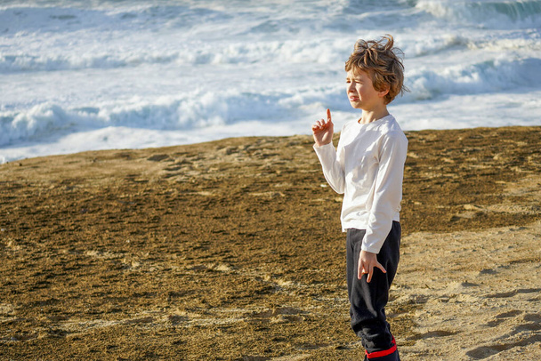 Samotny chłopiec stojący nad morzem z nieszczęśliwą twarzą. Wysokiej jakości zdjęcie - Zdjęcie, obraz