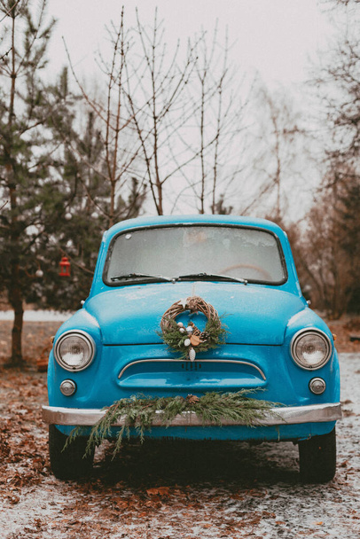 クリスマスツリーの枝、ギフトボックスクラフト包装紙花輪松モミの針で飾られたレトロな車。新年の旅。雪の森の中の車。グリーティングカード - 写真・画像