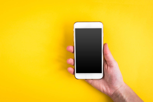 Mobile phone on yellow background. - Фото, изображение