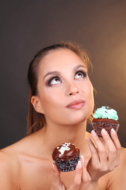 Portrait of beautiful young girl with chocolate cupcake on brown background  - Foto, Bild