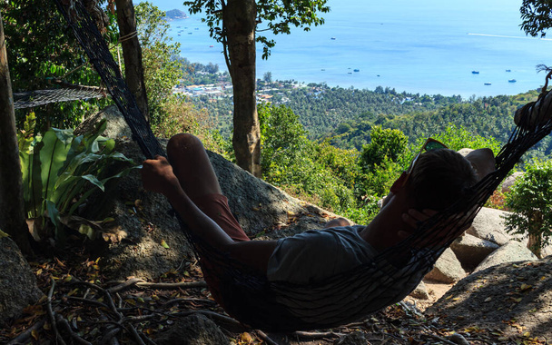 Ко Тао остров Манго точки зрения, человек качели в гамаке, зеленые пальмы и голубой морской воды. - Фото, изображение