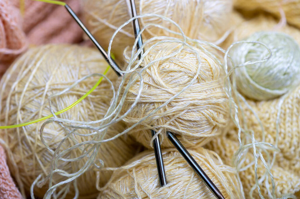 Knitting needles, skeins of yarn and knitted fabric, home needlework. Close-up, selective focus - Photo, image