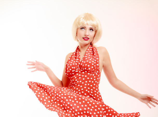 Beautiful pinup girl in blond wig and retro red dress dancing. Party. - Zdjęcie, obraz