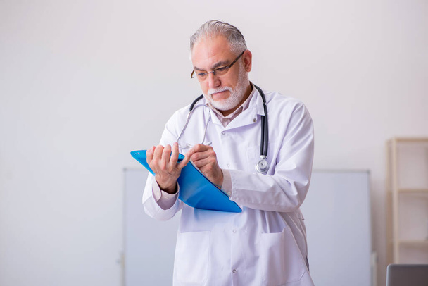 Old male doctor working in the clinic - Photo, Image