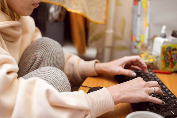 A woman works at a computer at home. The housewife is typing text on the keyboard. - Foto, Bild