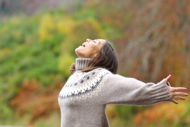 Profile of a middle age excited woman celebrating outstretching arms in the mountain in autumn season - Foto, immagini